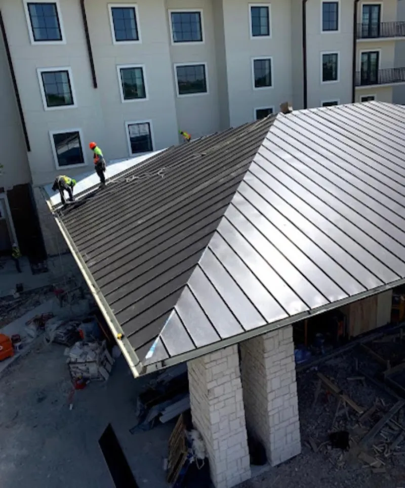 Crew installing standing seam metal roof panels on a commercial project in Orinda
